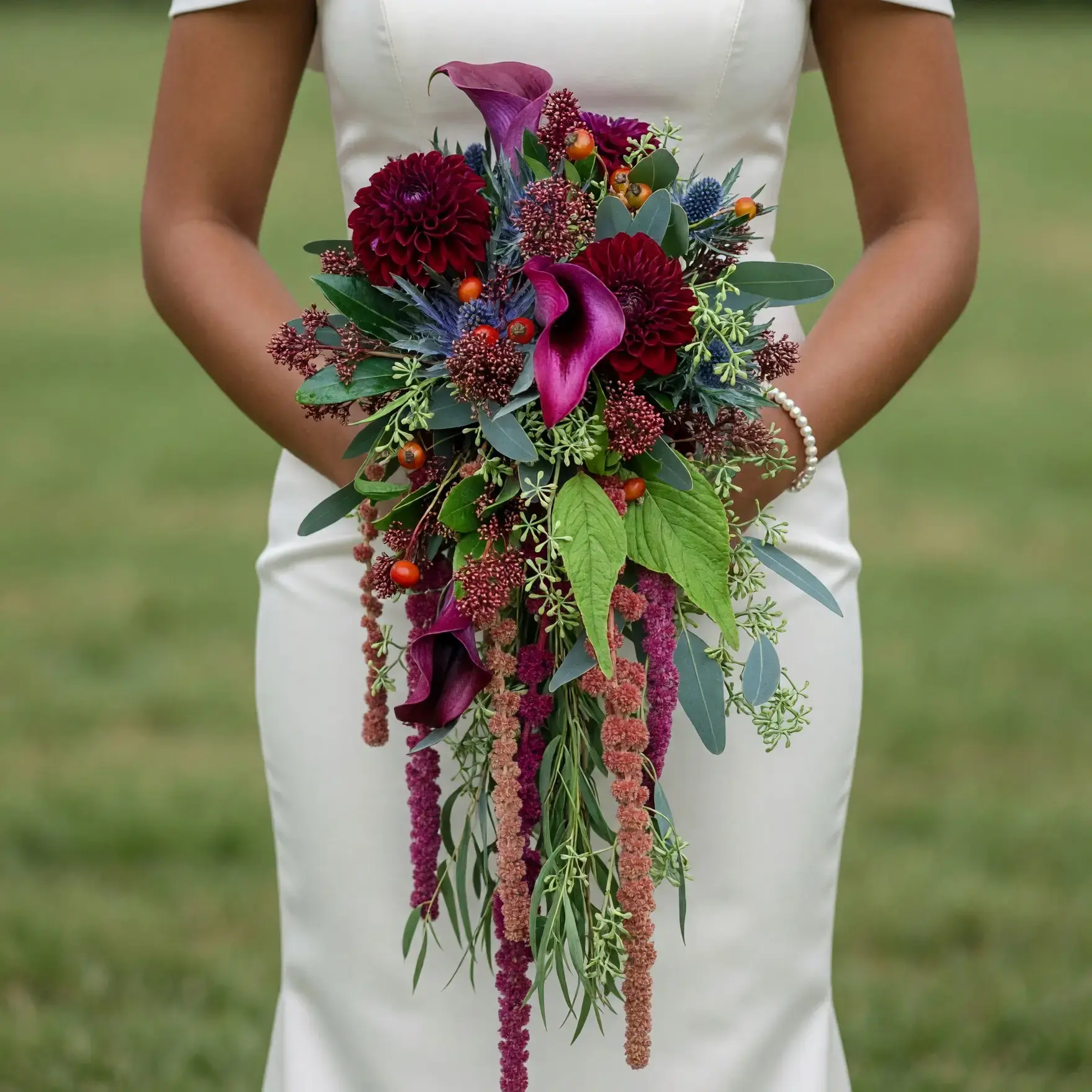 Bridal bouquet cost inspiration with burgundy dahlias, plum calla lilies, blue thistle, orange berries, eucalyptus, and cascading amaranthus