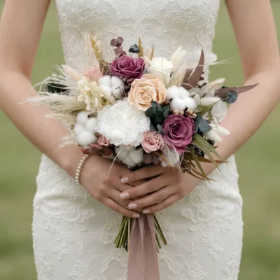 Boho bridal blooms bouquet with mauve and blush roses, ivory flowers, white cotton, eucalyptus, dried grasses, and muted rustic foliage.