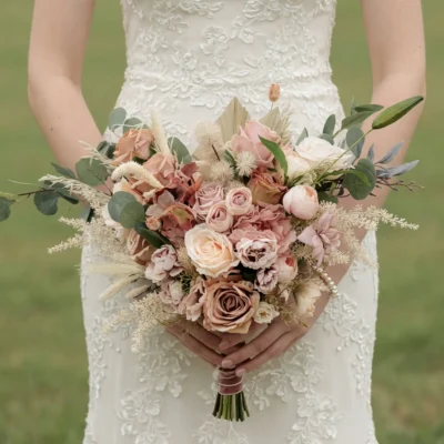 Popular wedding bouquets in boho style with dusty blush roses, pink hydrangea, eucalyptus, cream dried grasses, and romantic neutral bridal flowers.