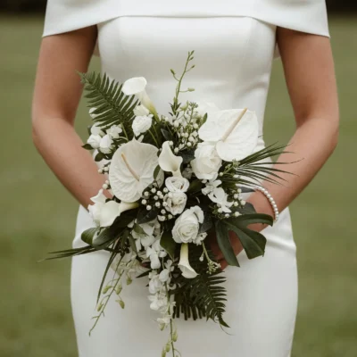 popular wedding bouquets with white anthurium calla lilies roses white berries fern palm leaves and monstera greenery for a tropical bride