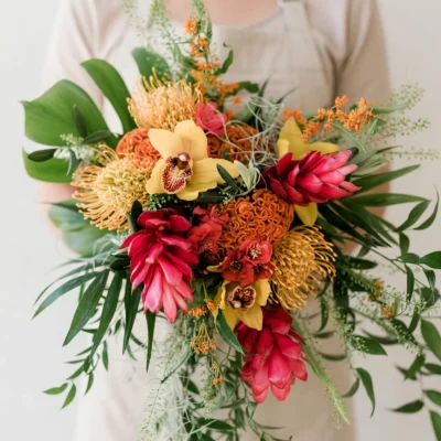 boho style flowers tropical bridal bouquet with red ginger golden orchids orange pincushion protea and loose palm greenery