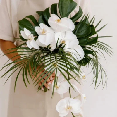 popular wedding bouquets with white phalaenopsis orchids cascading blooms monstera leaves and sweeping tropical palm fronds