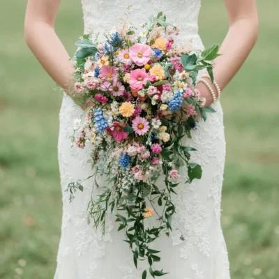 Bridal flowers bouquets with colorful dried pink, blue, peach and white wedding flowers in a romantic cascading meadow design