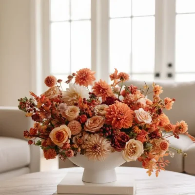 Fall flower arrangement Vancouver with apricot and peach blooms, cream roses, burgundy accents and berries arranged in a white pedestal vase.