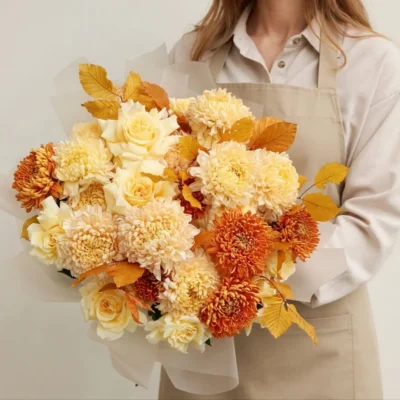 Luxury autumn flower bouquet with cream yellow roses, ivory and burnt-orange chrysanthemums, and golden foliage, wrapped in neutral paper at The Bloomerie Vancouver.