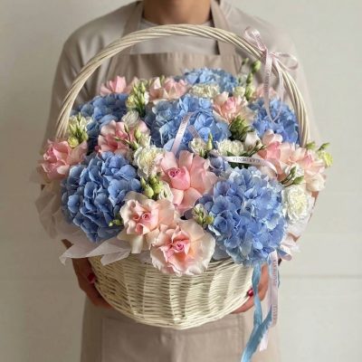 Hydrangea flower basket Vancouver with blue hydrangeas, blush pink roses and white flowers arranged in a light woven handled basket